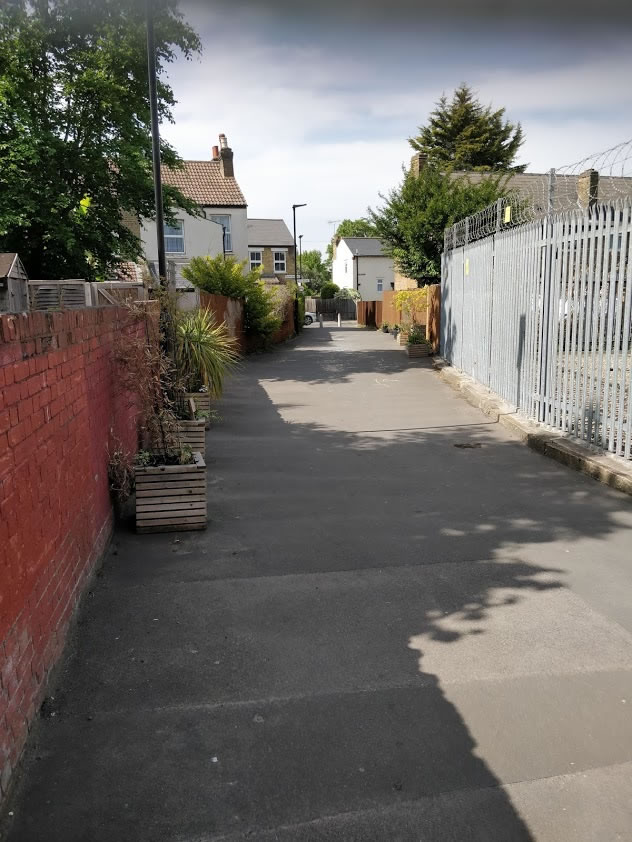 A path with trees on the side of a building  Description automatically generated