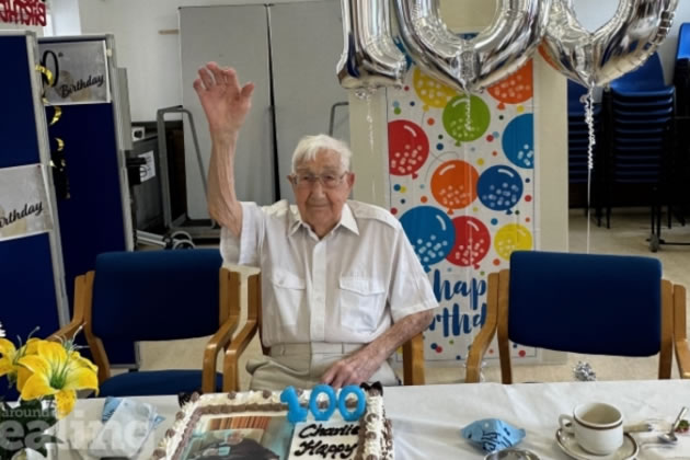 Centenarian Charlie Hatfield with birthday cake and balloons