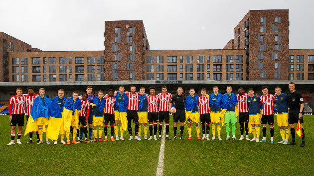 The two teams line up together ahead of the game